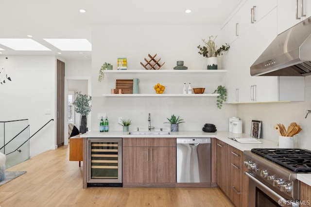 kitchen with wine cooler, brown cabinets, stainless steel appliances, under cabinet range hood, and a sink