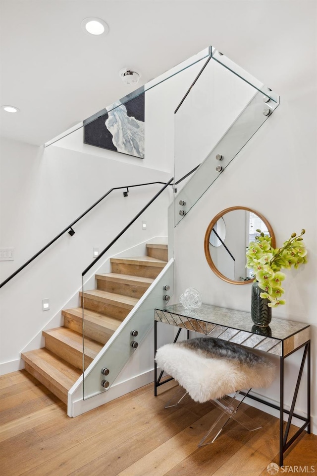 stairs featuring wood finished floors and recessed lighting