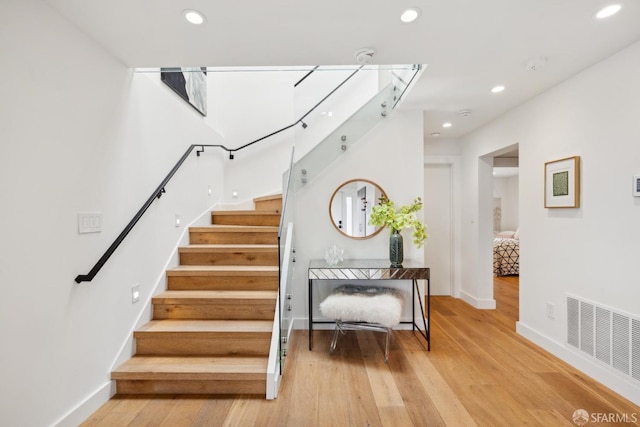 stairway with wood finished floors, visible vents, and recessed lighting