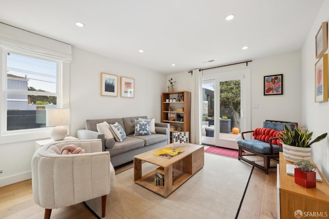 living area with baseboards, light wood-type flooring, and recessed lighting