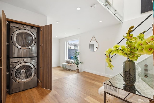 clothes washing area with recessed lighting, laundry area, stacked washer / dryer, baseboards, and hardwood / wood-style floors