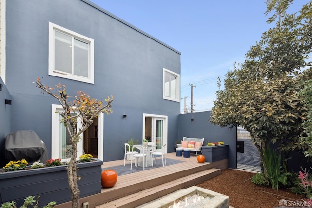 rear view of property featuring an outdoor living space, a deck, and stucco siding