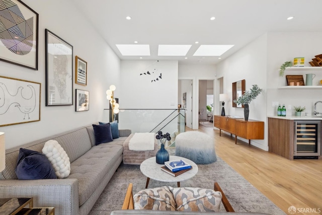 living area with light wood-type flooring, a skylight, beverage cooler, and recessed lighting