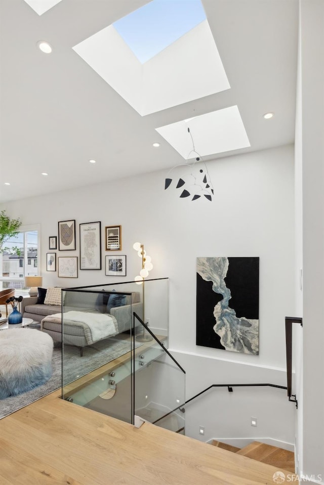 living area with a skylight, wood finished floors, and recessed lighting