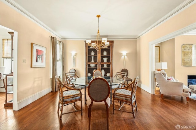 dining room featuring an inviting chandelier, dark wood finished floors, baseboards, and ornamental molding