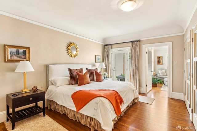bedroom with baseboards, access to outside, crown molding, and wood finished floors