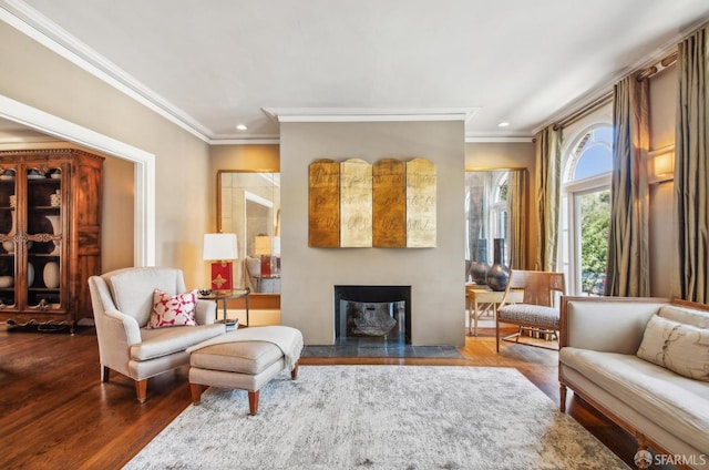 interior space featuring recessed lighting, crown molding, wood finished floors, and a glass covered fireplace