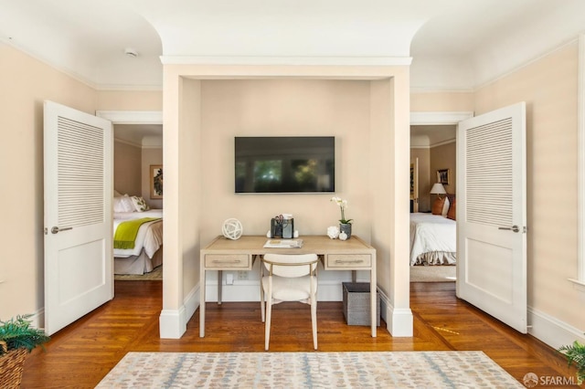 office area with baseboards, crown molding, and wood finished floors