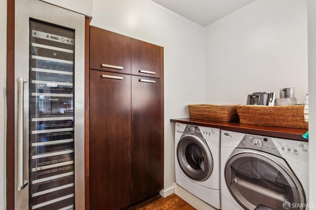 washroom with washing machine and dryer, cabinet space, dark wood-style flooring, baseboards, and wine cooler