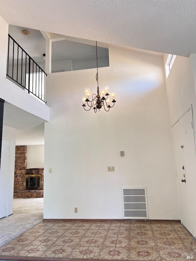 interior space with a chandelier, a towering ceiling, and a stone fireplace