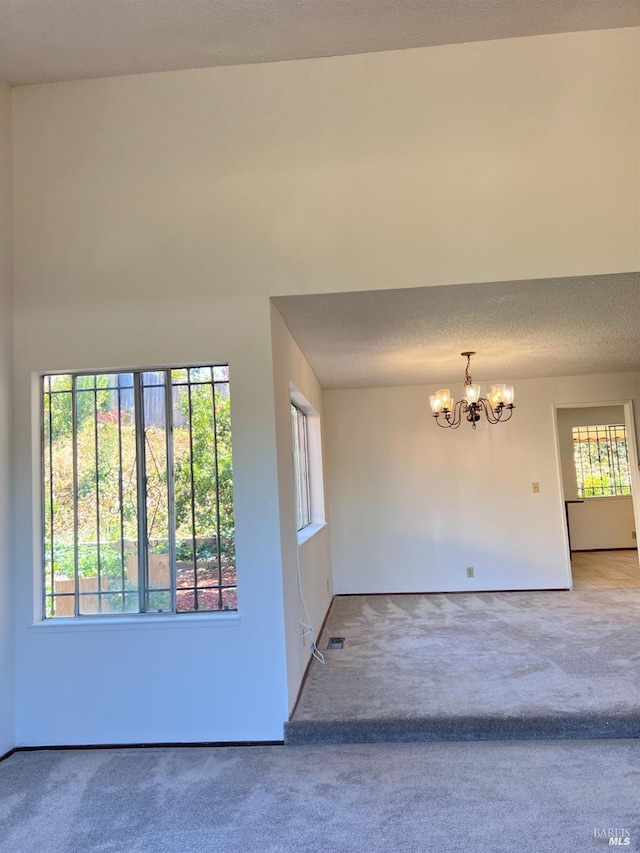 unfurnished room featuring carpet floors, an inviting chandelier, and a healthy amount of sunlight