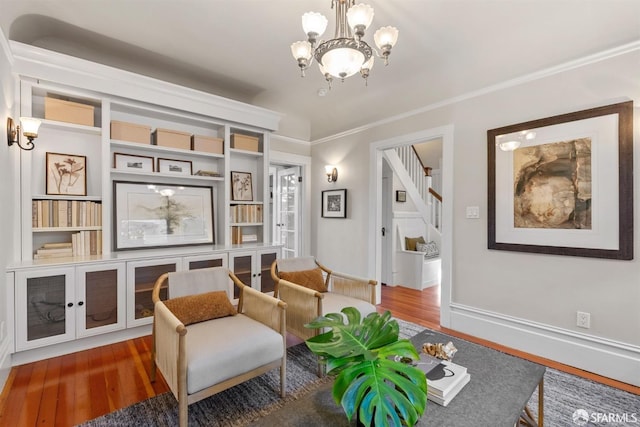 living area with crown molding, hardwood / wood-style floors, and a notable chandelier