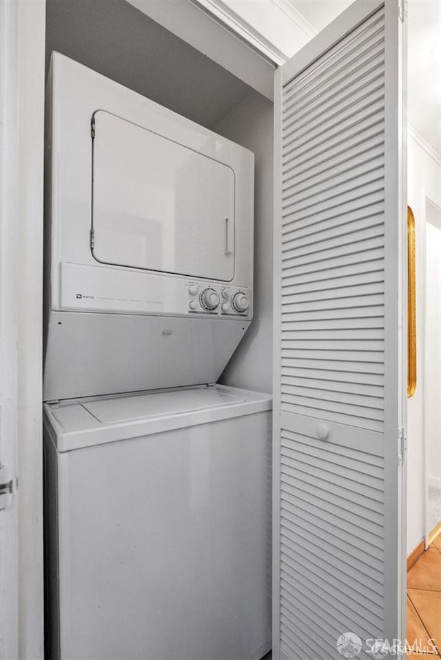 laundry room featuring stacked washer / drying machine and light tile patterned floors