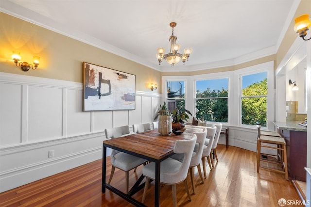 dining space with crown molding, hardwood / wood-style floors, and a notable chandelier