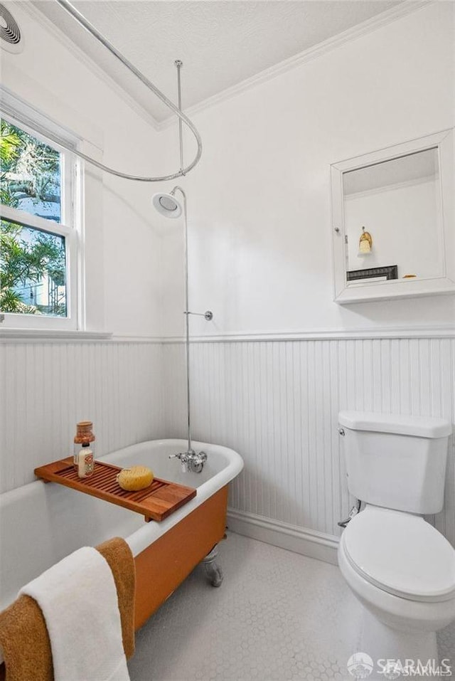 bathroom with tile patterned flooring, crown molding, toilet, and a bathing tub