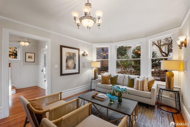 living room with wood-type flooring, ornamental molding, and a notable chandelier