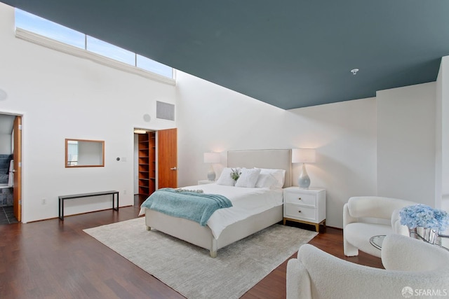 bedroom with dark wood finished floors, a spacious closet, and a high ceiling