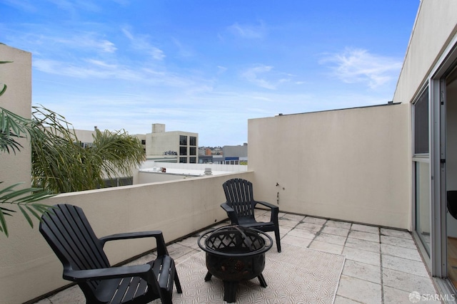 view of patio / terrace with an outdoor fire pit and a balcony