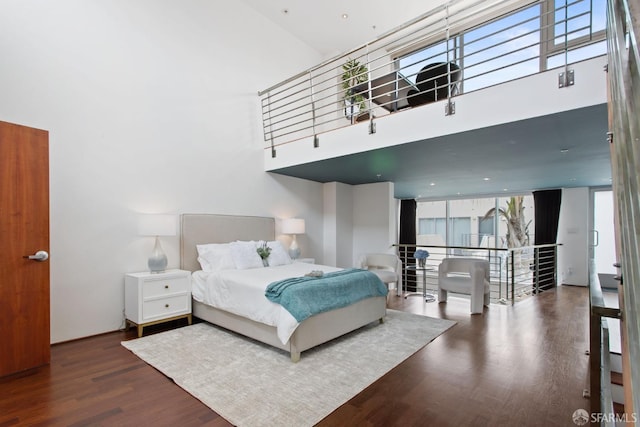 bedroom featuring a towering ceiling and wood finished floors