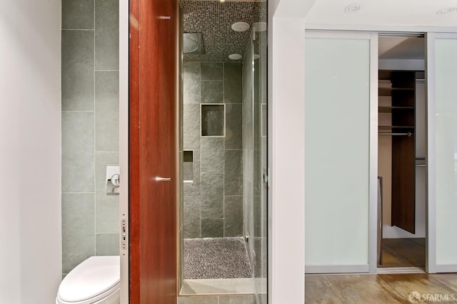 full bathroom featuring a stall shower, tile walls, and toilet