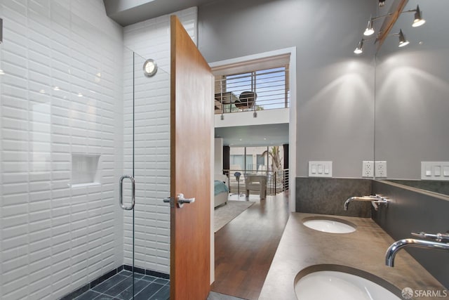 ensuite bathroom with double vanity, tiled shower, a sink, and connected bathroom