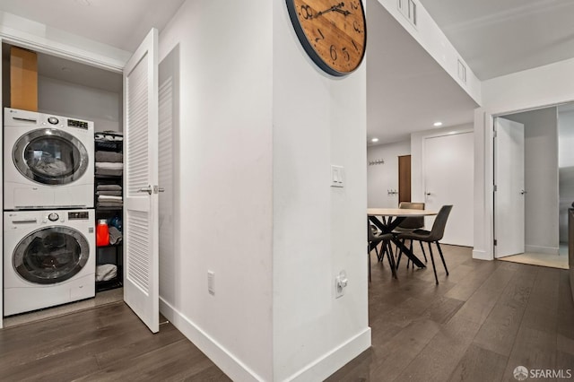 laundry room featuring baseboards, dark wood-style flooring, laundry area, and stacked washing maching and dryer