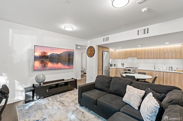 living area featuring visible vents, baseboards, and wood finished floors