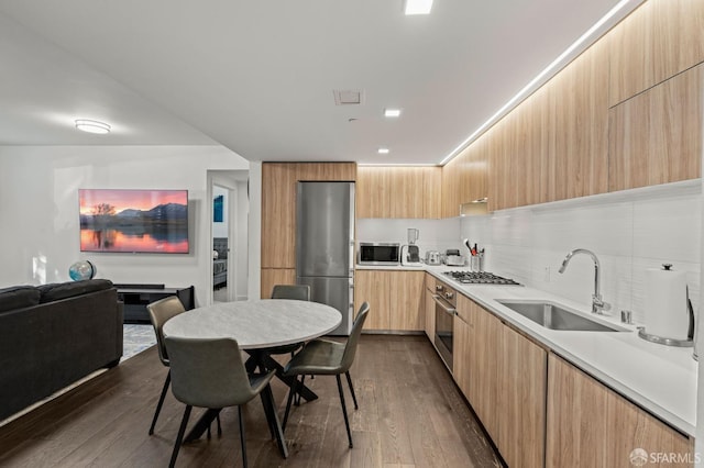 kitchen featuring light brown cabinetry, stainless steel appliances, modern cabinets, and a sink