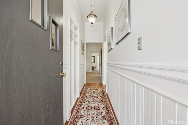 corridor featuring a decorative wall and a wainscoted wall
