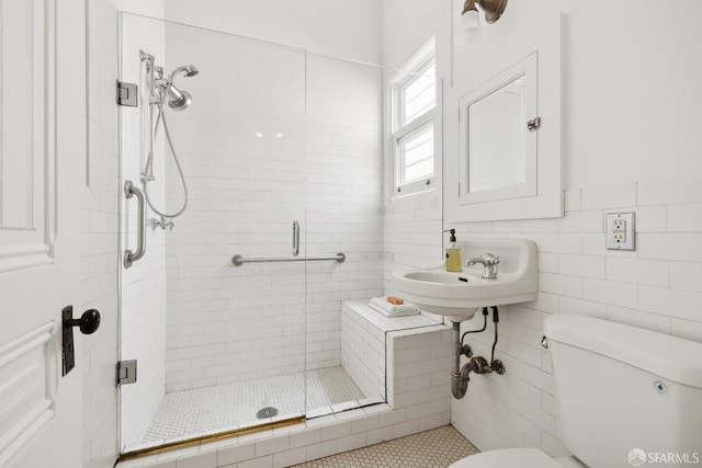 full bathroom with toilet, a stall shower, tile walls, a sink, and tile patterned flooring