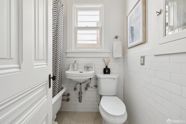 full bathroom featuring tile patterned flooring, toilet, tile walls, and a sink