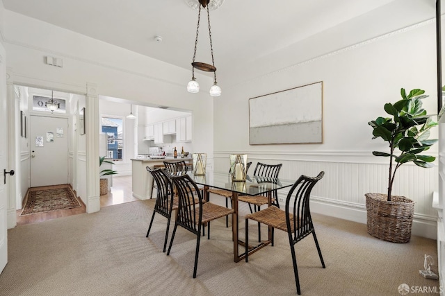 dining space featuring light colored carpet and wainscoting