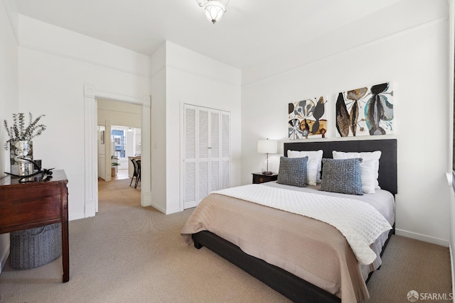 bedroom featuring light colored carpet, a closet, and baseboards