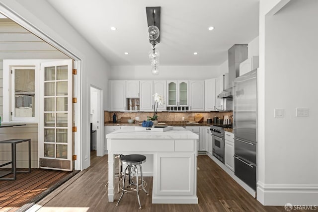 115 Magnolia St, San Francisco, CA 94123 - kitchen with high quality appliances, white cabinetry, a kitchen bar, tasteful backsplash, and dark wood-style floors