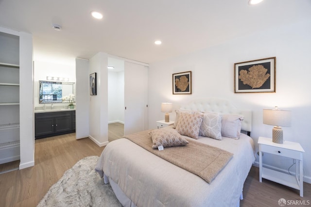 bedroom featuring hardwood / wood-style flooring, connected bathroom, and sink