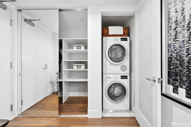 washroom with stacked washer and dryer, laundry area, and wood finished floors