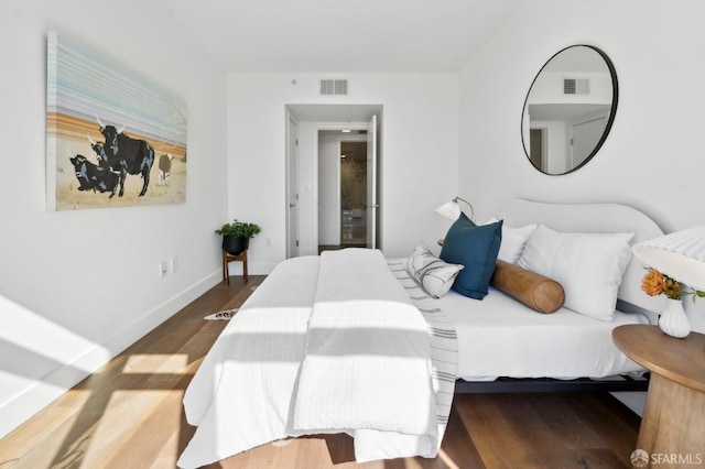 bedroom featuring wood finished floors, visible vents, and baseboards