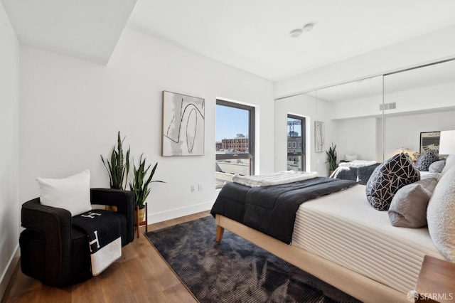 bedroom with a closet, visible vents, baseboards, and wood finished floors