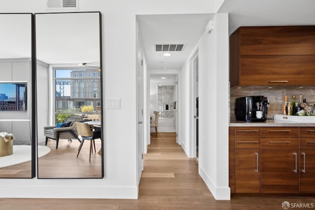 bar featuring baseboards, visible vents, decorative backsplash, and wood finished floors