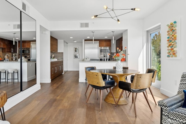 dining area with baseboards, a notable chandelier, visible vents, and wood finished floors