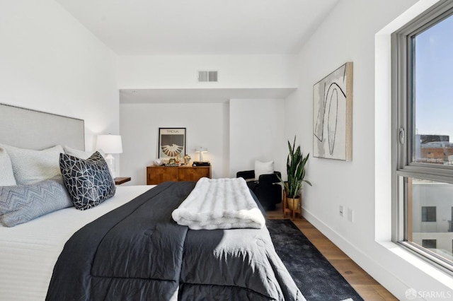 bedroom featuring wood finished floors, visible vents, and baseboards