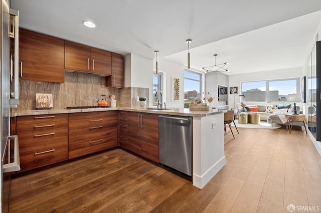 kitchen featuring a peninsula, dark wood-style flooring, a sink, appliances with stainless steel finishes, and brown cabinetry