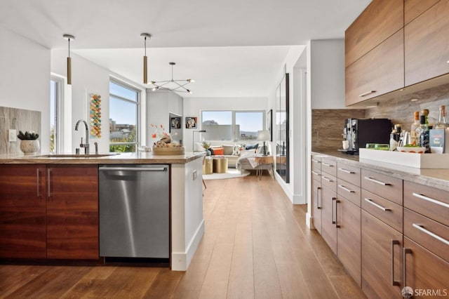 kitchen with decorative backsplash, modern cabinets, wood finished floors, stainless steel dishwasher, and a sink