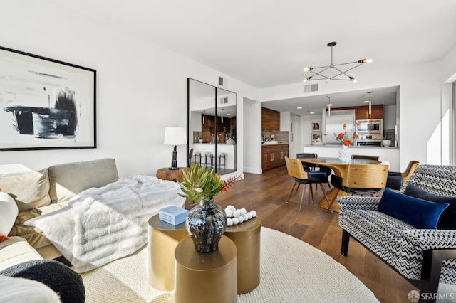 living area featuring an inviting chandelier, visible vents, and dark wood-style flooring