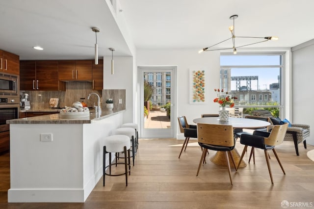 kitchen with appliances with stainless steel finishes, light wood-type flooring, a healthy amount of sunlight, and backsplash