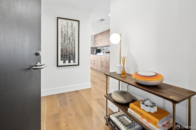 hall featuring light wood-style floors, visible vents, and baseboards