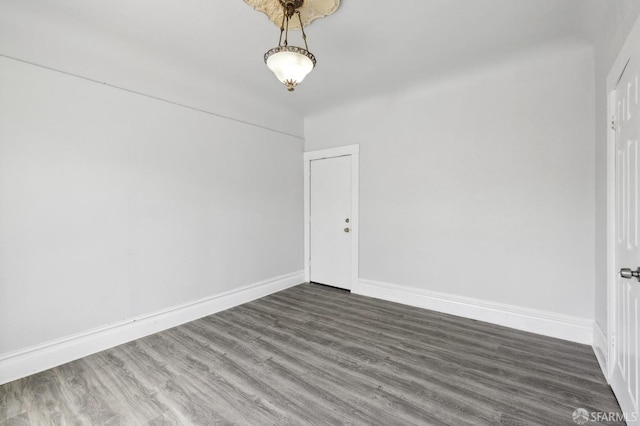 unfurnished room featuring baseboards and dark wood-type flooring