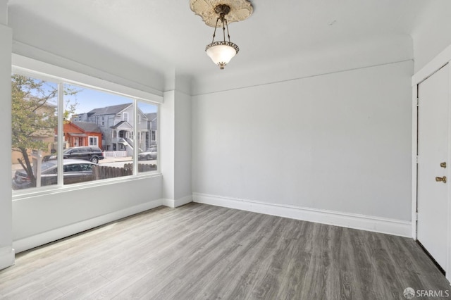 unfurnished dining area featuring baseboards and wood finished floors