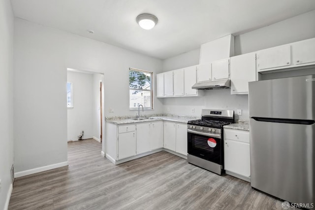 kitchen with a sink, stainless steel appliances, light wood-type flooring, and under cabinet range hood