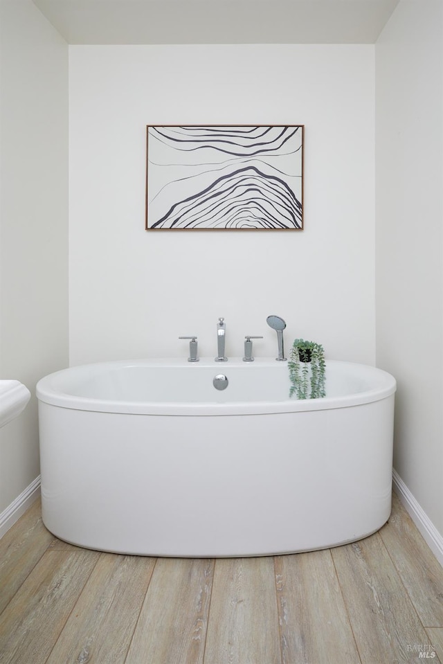 bathroom featuring hardwood / wood-style flooring and a tub to relax in